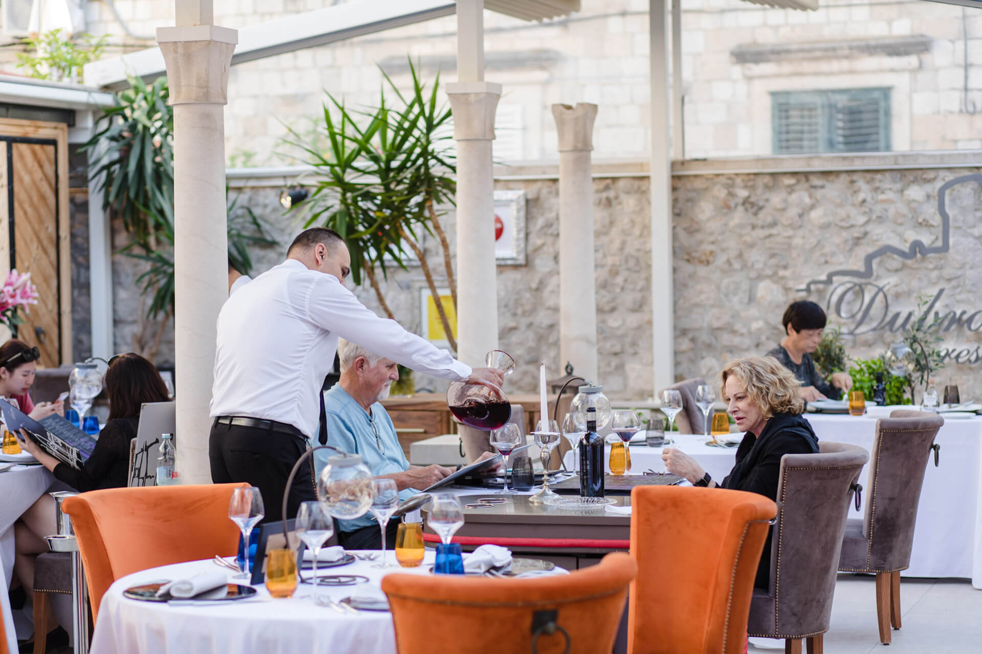 Restaurant Dubrovnik waiter poruing red wine to two table guests