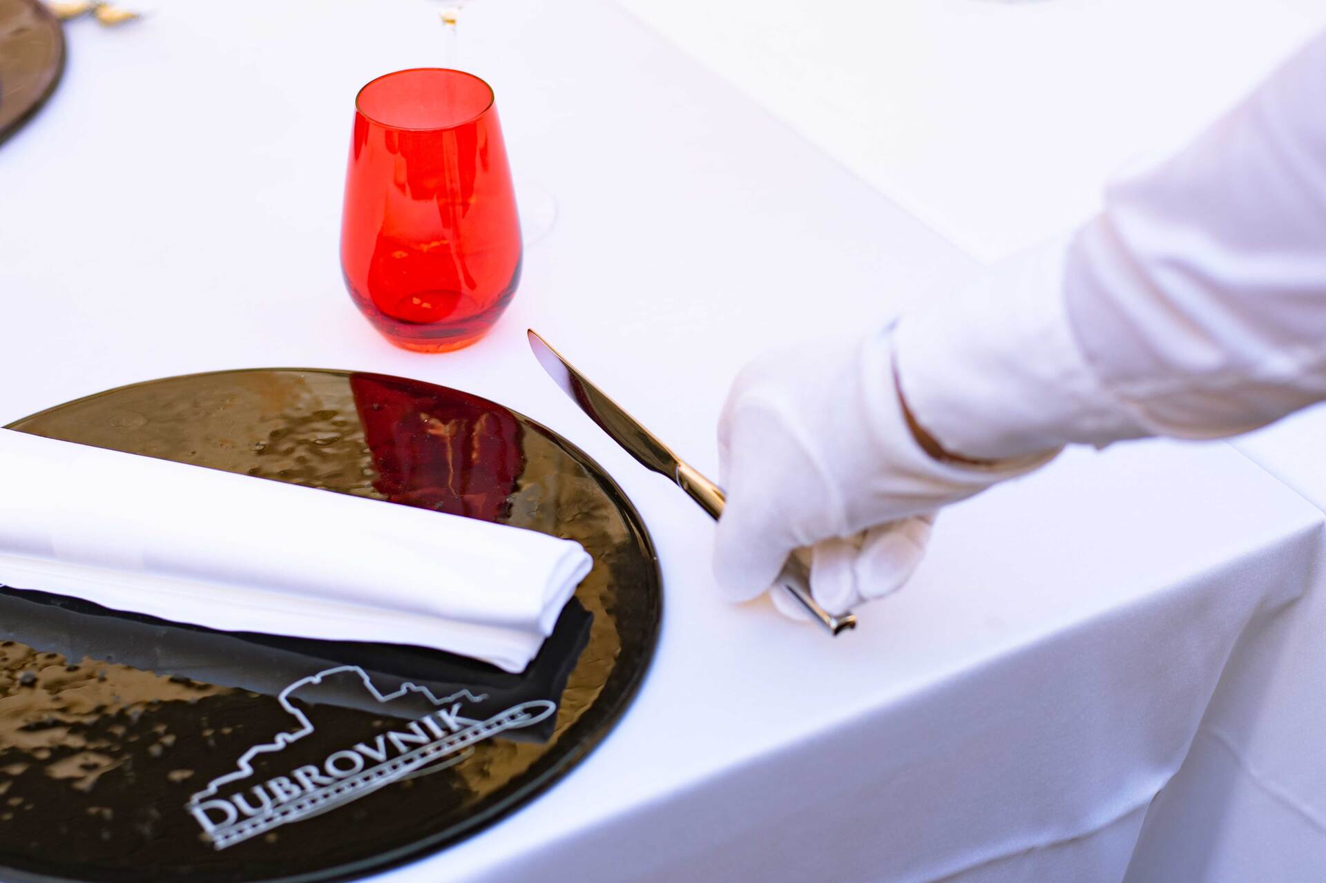 Restaurant Dubrovnik waiter getting table ready for guests, Restaurant Dubrovnik plate with logo on the bottom side